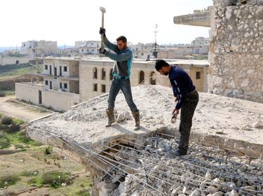 Men work on a damaged building in the northwestern province of Idlib, Syria, December 27, 2014, photo by Mahmoud Hebbo/Reuters