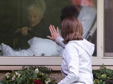 A woman visits her mother who has tested positive for coronavirus at a Seattle-area nursing home, the epicenter of one of the biggest outbreaks in the United States, in Kirkland, Washington, March 11, 2020, photo by Jason Redmond/Reuters