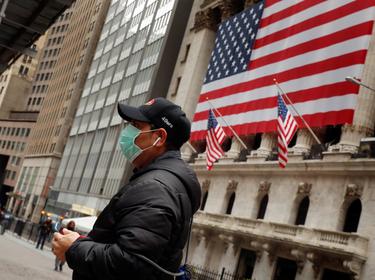 A man wears a mask while walking past the New York Stock Exchange in New York City, March 17, 2020, photo by Lucas Jackson/Reuters