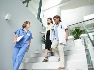 Team of young doctors walking down the stairs in a medical facility, photo by AJ_Watt/Getty Images
