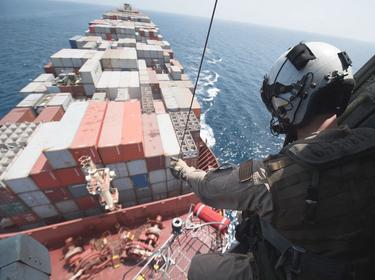 A U.S. Naval Air Crewman lowers a litter onto the deck of a merchant ship in the Gulf of Aden