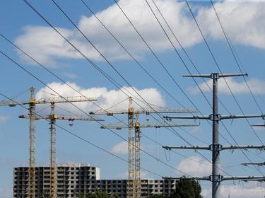 Building cranes and power lines connecting high-tension electricity pylons next to a construction site in Kyiv, Ukraine, July 10, 2020, photo by Valentyn Ogirenko/Reuters