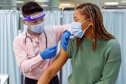 Young African-American woman receiving a COVID vaccination at a public clinic, photo by Fly View Productions/Getty Images