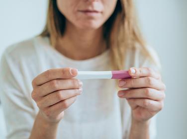 A concerned young woman looks at a pregnancy test, photo by VioletaStoimenova/Getty Images