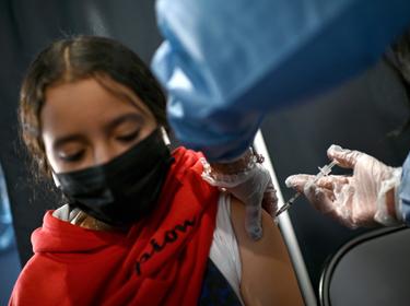 Esme, 11, receives a COVID-19 vaccination at the American Museum of Natural History's kids vaccination site in New York, November 29, 2021, photo by Anthony Behar/Sipa USA via Reuters Connect