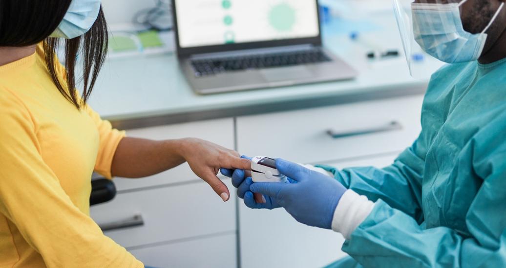 A doctor using a pulse oximeter on a patient's finger to measure oxygen saturation, photo by Sabrina Bracher/Getty Images