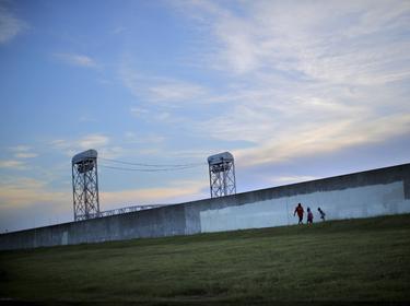 Lower Ninth Ward area residents walk by the reconstructed wall of a levee at the Lower Ninth Ward canal in New Orleans, Louisiana, August 16, 2015, photo by Carlos Barria/Reuters