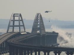 A helicopter drops water to extinguish fuel tanks ablaze on the Kerch bridge in the Kerch Strait, Crimea, October 8, 2022, photo by Stringer/Reuters