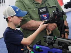 A child looks at a pistol conversion kit during the National Rifle Association annual convention in Houston, Texas, May 27, 2022, photo by Shannon Stapleton/Reuters