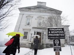 People walk past a sign prohibiting firearms and weapons inside the State Legislature in Montpelier, Vermont, March 13, 2018, photo by Christinne Muschi/Reuters