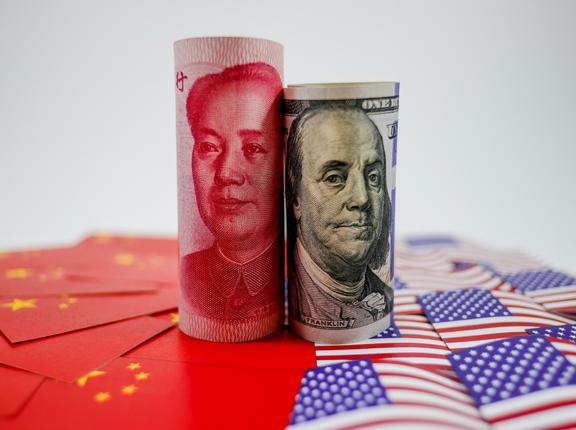 China yuan banknote on China flags and U.S. dollar banknote on United States flags, photo by Dilok Klaisataporn/Getty Images