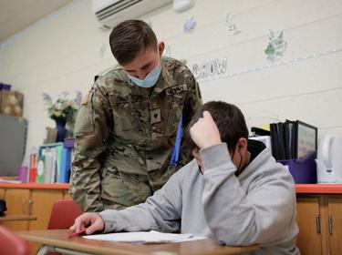 National Guard Specialist Austin Alt assists a student as he fills in as a substitute teacher due to staffing shortages caused by COVID-19 at Pojoaque Valley Middle School in Pojoaque, New Mexico, January 28, 2022, photo by Adria Malcolm/Reuters