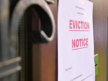 Close up of an eviction notice hanging on a door, photo by Vyacheslav Dumchev/Getty Images