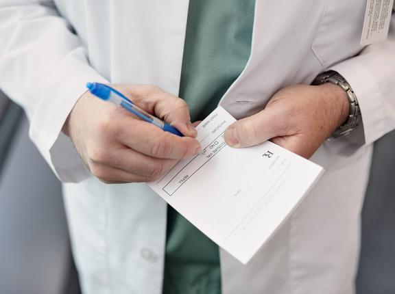 Close up of a doctor filling out a prescription, photo by francisblack/Getty Images