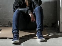 Depressed female sitting on floor with a hoodie covering her face, photo by Pixel-Shot/Adobe Stock