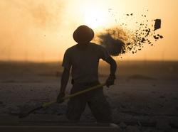 A water fuels system maintenance craftsman shovels dirt and concrete away from a construction site in Southwest Asia