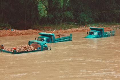 Dump trucks submerged in a muddy river, photo by Jean Beller/Unsplash