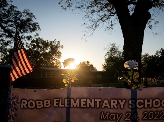White roses and an American flag are seen in a memorial outside Robb Elementary, where a gunman killed 19 children and two teachers, in Uvalde, Texas, November 29, 2022, photo by Marco Bello/Reuters