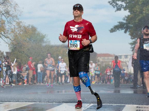 A member of Team Red, White and Blue runs through a cooling shower of water at the Marine Corps Marathon in Washington, D.C., October 30, 2016, photo. by Lance Cpl. Timothy Smithers/U.S. Marines