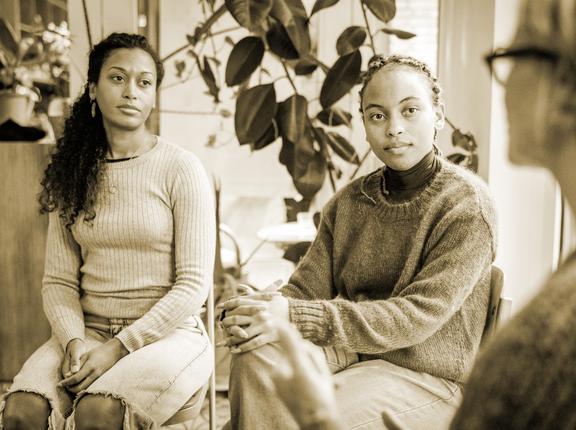 Two women attending a group therapy session attentively listen to a fellow attendee share her feelings and experiences. Photo by Gunnar Svanberg Skulason / Getty Images