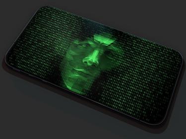Green face peering out of machine code on cell phone, photo by Devrimb/Getty Images